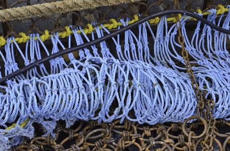 Industrial detail Coiled blue rope by rusty links of iron net on trawler in harbor